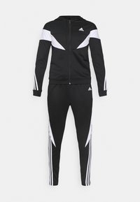 Survêtement Adidas noir avec détails blancs, comprenant un sweat à capuche zippé et un pantalon fuselé assorti avec le logo Adidas sur le haut et le pantalon.
