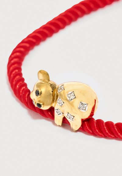 Χρυσό γούρι χοίρου με μαύρα μάτια και κρυσταλλικά διακοσμητικά σε στριμμένο κόκκινο κορδόνι. Το γούρι έχει γυαλιστερό φινίρισμα και στρογγυλό σχήμα.