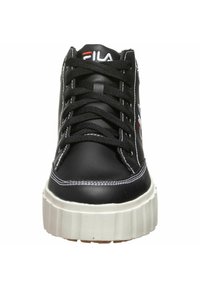 Musta nahkakengät valkoisilla ompeleilla, joissa on paksu valkoinen pohja ja näkyvät nauhat. Logo kielen päällä punaisena ja valkoisena.