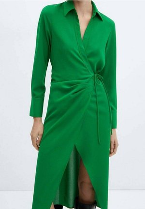 Abito avvolgente verde con maniche lunghe, colletto, dettaglio di legatura laterale e uno spacco alto su un lato, realizzato in tessuto liscio che cade elegantemente.