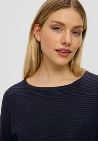 Marineblaue, gerippte Oberteil mit Rundhalsausschnitt. Der Stoff ist weich und strukturiert, mit subtilen horizontalen Linien. Eignet sich für die Freizeit.