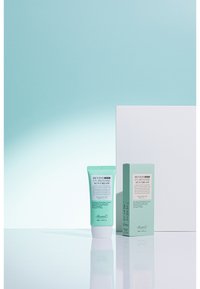 Benton UV Defense Solkräm i en ljus mintgrön tub med ett vitt lock, tillsammans med en matchande förpackning, med text och ikoner som detaljerar ingredienser.