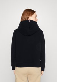 Felpa con cappuccio blu navy realizzata in tessuto morbido, con un ampio cappuccio, polsini a coste e un design minimalista; vista posteriore fornita.
