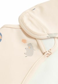 Bavaglino in silicone di un rosa pallido con illustrazioni di animali, bordi arrotondati e accenti a pois; presenta una superficie testurizzata e facile da pulire.