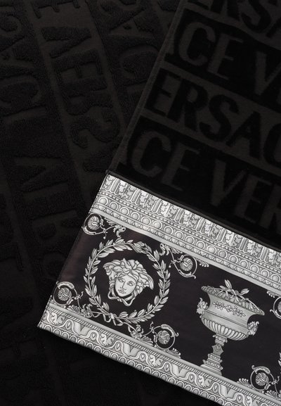 Μαύρο ύφασμα με ανάγλυφο το κείμενο "VERSACE" και μαύρο-άσπρο περιθώριο με σχέδιο κεφαλής Μέδουσας και διακοσμητικού αμφορέα.