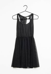 Svart klänning med figursydd överdel, ärmlös design och en utsvängd kjol i genomskinligt tyg. Har en dragkedja bak.