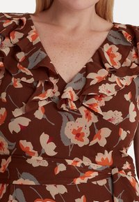 Hnědá květinová šaty s volánkovým výstřihem; obsahuje krémové a oranžové květy na texturované látce; zúžený pas s detailem na zavázání.
