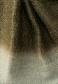 Tessuto morbido e peloso con sfumature che vanno dal verde oliva in alto al grigio chiaro in basso, piegato con texture e ombre visibili.