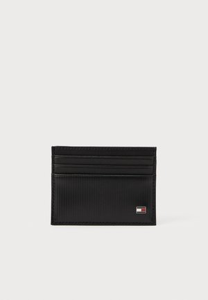 Cardholder din piele neagră cu textură striată, având patru sloturi pentru carduri și un accent mic cu logo. Design minimalist cu linii curate.
