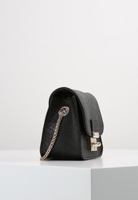 Czarna torebka ze skóry o fakturze, z klapą na zapięcie, srebrnymi dodatkami i łańcuszkowym paskiem, o trójkątnym kształcie i subtelnym tłoczeniu.