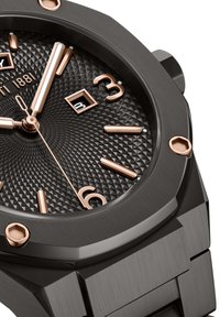 Orologio nero con quadrante nero texturizzato, indicatori e lancette delle ore in oro rosa. Presenta una finestra per la data e accenti hardware esagonali.