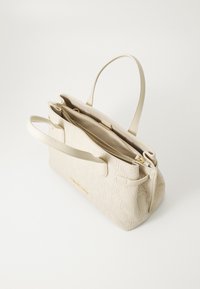 Beige handbag with embossed logo pattern, structured shape, dual handles, and zip closure. Textured material with gold hardware accents.