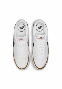 Sneakers bianchi con loghi Nike neri e arancioni, texture liscia, punta rotonda e dettagli dorati sulla suola. I lacci sono bianchi.