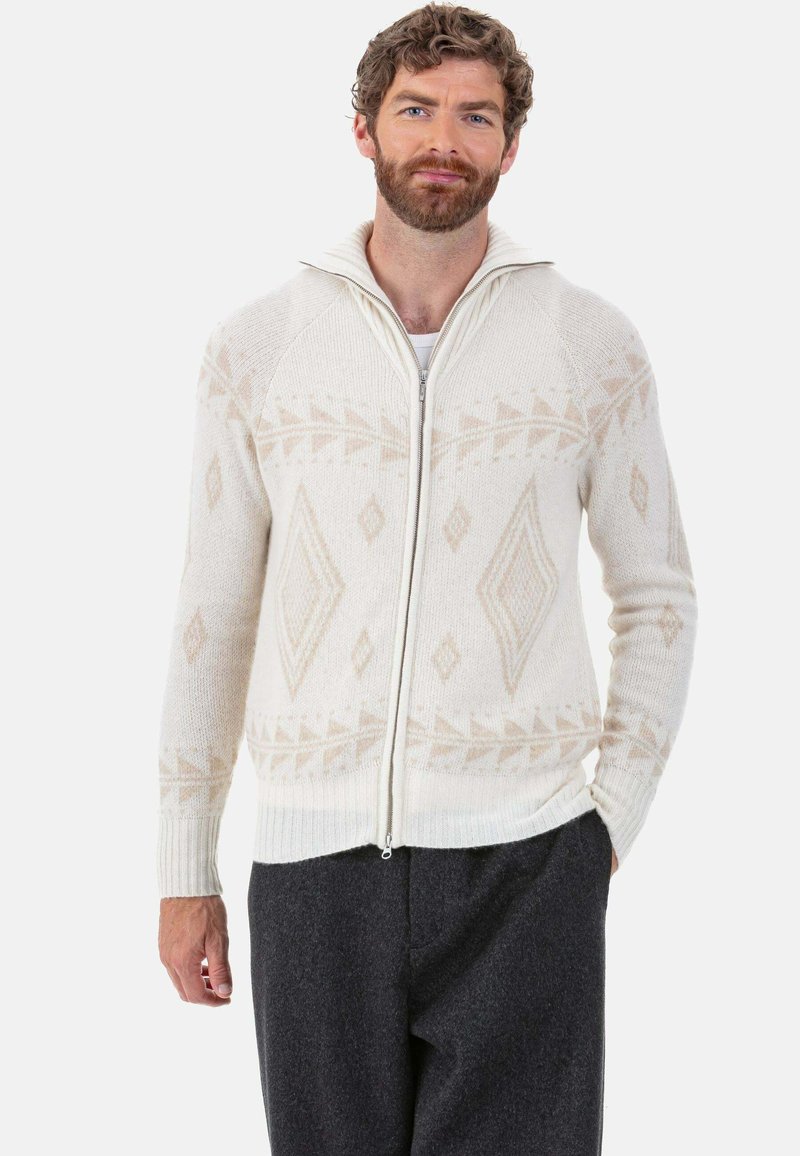 Pull à fermeture éclair couleur crème avec motifs géométriques en beige, poignets et col côtelés ; texture tricotée offrant chaleur et confort.