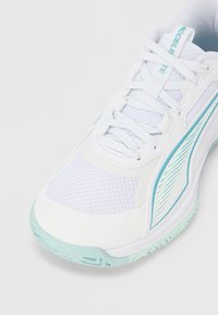 Λευκό αθλητικό παπούτσι από δίχτυ και συνθετικό υλικό. Διαθέτει φωτεινές μπλ ε λεπτομέρειες, υφή στην επιφάνεια και στρογγυλεμένη μύτη. Εμφανή κορδόνια.