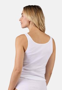 White tank top made of soft fabric with a rounded neckline and wide straps, featuring a smooth texture and a fitted cut.