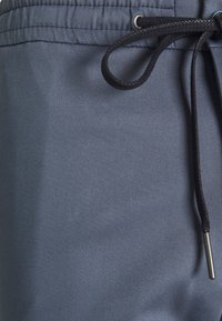 Mörkgrå shorts för män tillverkade av ett smidigt material, med resårmidja, dekorativ dragsko och metallaglet på snöret.