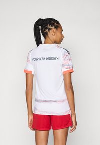 Maglia del FC Bayern München, bianca con accenti rossi, caratterizzata da un design a fantasia. Maniche corte, scollo rotondo, vestibilità aderente, logo sul retro.