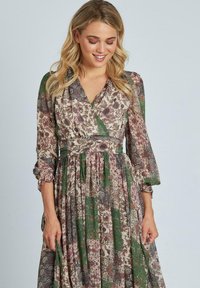 Abito maxi floreale e con motivo in tonalità di verde, bordeaux e crema. Presenta maniche lunghe, un design avvolgente e una gonna affollata.