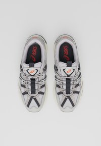 Harmaat urheilukengät, joissa on hengittävä verkkomateriaali, mustat yksityiskohdat, nauhat ja vaalea pohja, jossa on Asics-logo sisäpohjassa.