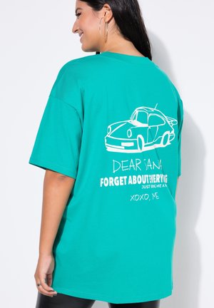 Turkoois oversized t-shirt met een witte autografiek en tekst op de achterkant. Korte mouwen, ronde halslijn en zachte katoen stof.