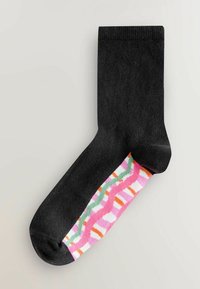 Schwarze Socke mit gerippter Textur und einem farbenfrohen Musterakzent in Pink, Weiß, Grün und Orange an der Seite.