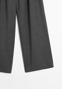 Grau wollene Hose mit weitem Schnitt. Der Stoff hat eine weiche Textur und eine glatte Oberfläche, geprägt von einem sauberen, maßgeschneiderten Look.