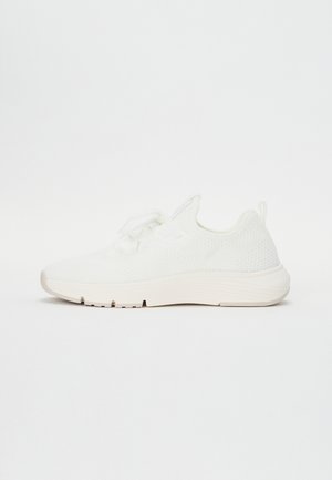 Hvid letvægtsstrik-sneaker med en tyk sål og snørelukning vist fra siden på en hvid baggrund.