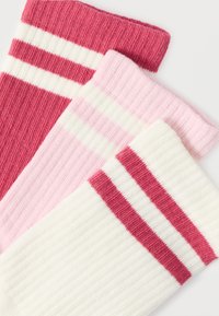 Τρία ζευγάρια κάλτσες με ριγέ υφή: σκούρο ροζ με λευκές ρίγες, ανοιχτό ροζ και λευκό με ροζ ρίγες. Μαλακή υφή και διάφορες αποχρώσεις του ροζ.