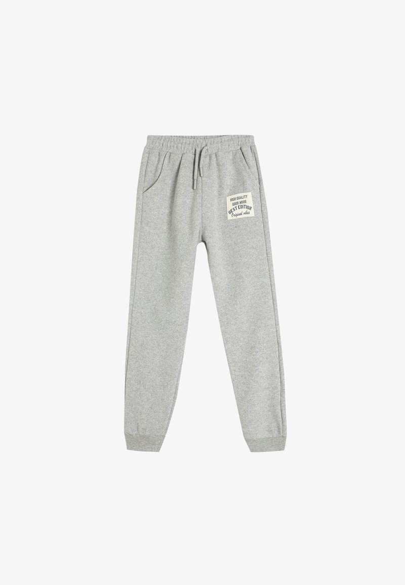Grå sweatpants med elastisk talje, snoretræk, sidelommer og et lille mærke med tekst på venstre lår. Blød stofstruktur.