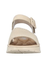Beige sports sandals with a textured knit upper, adjustable buckle strap, and cushioned insole on a flexible sole.