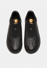 Sneaker in pelle nera con texture liscia, design curvo e sei fori per i lacci. Presenta un logo arancione e accenti di cucitura discreti.