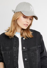 Light gray baseball cap with white embroidery, made of soft fabric. The cap features a curved brim and an adjustable strap at the back.