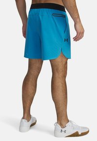 Pantalones cortos deportivos azules fabricados con un tejido ligero, que cuentan con una cinturilla negra, un bolsillo lateral con cremallera negra y un patrón perforado cerca del dobladillo.