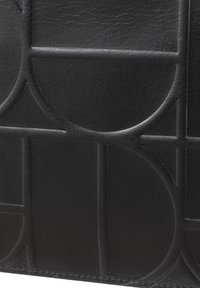 Portefeuille en cuir noir avec un motif géométrique en relief, texture lisse et bords nets, mettant en avant des designs circulaires et linéaires.