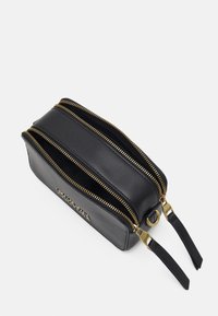 Borsa cosmetica in pelle nera con due cerniere dorate, forma rettangolare piatta e due manici neri. Presenta un logo impresso sul lato.