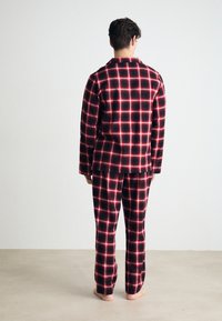 Röd och svart rutigt flanellpyjamasset med långa ärmar och byxor, som har en avslappnad passform och en mjuk textur.