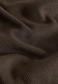 Soft, dark brown ribbed fabric with fine vertical lines and gentle folds creating a textured surface.