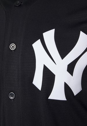 Schwarzes Sporttrikot mit Knöpfen und großem weißem ineinander verschlungenem "NY"-Logo, das auf der Brust aufgestickt ist.