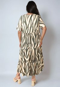 Maxi-jurk met een gelaagde ontwerp, met een wit en groen zebra-strikpatroon, korte mouwen en een comfortabele pasvorm, gecombineerd met sandalen met blokhak.