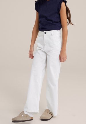 Witte wijde jeans met een hoge taille, gecombineerd met een marineblauwe t-shirt met ruches aan de mouwen. Tan instap schoenen maken de outfit compleet.