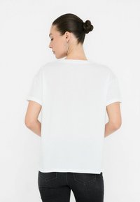 Maglietta bianca a maniche corte con scollo rotondo e vestibilità comoda. Tessuto morbido, orli rifiniti e texture liscia.