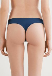 Marineblauwe bikini onderkant van een gladde, rekbare stof. Heeft een lage taille en minimale bedekking aan de achterkant, naadloos ontwerp.