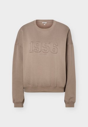 Bluza taupe cu decolteu rotund, mâneci lungi, manșete și tiv cu striații, având cusături în relief cu "1956" în centrul părții din față.