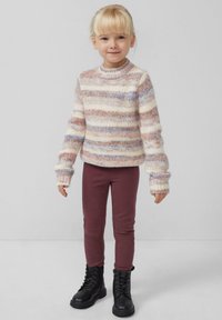 Multicolore gebreide trui met tinten van crème, roze en blauw, gecombineerd met bordeaux leggings en zwarte veterschoenen. Comfortabele pasvorm en lange mouwen.