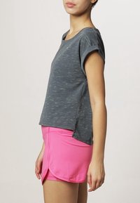 Grå, kortärmad topp med en lätt textur, parat med en rosa, sportig kjol med lagerdesign och sidofickor för rörelse.