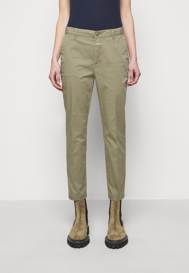 Olivgröna byxor med rak passform, framfickor och knappstängning. Kompletteras av bruna mocka ankelskor med svarta detaljer.