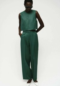 Grünes Zweiteiler-Outfit mit einem kurvenreichen, ärmellosen Top und hoch taillierten, weit geschnittenen Hosen, hergestellt aus glattem Stoff, mit seitlichen Taschen.