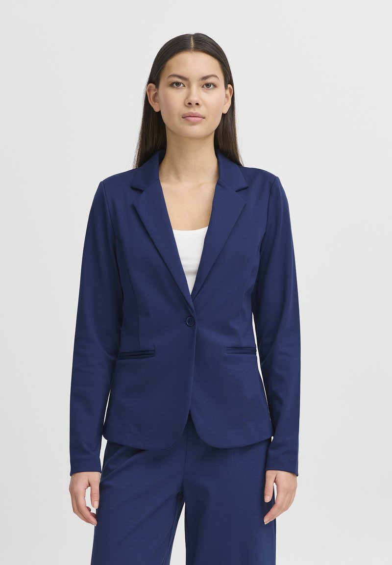 Blazer azul marino en tela suave, con cierre de un botón en la parte delantera, solapas con muesca y dos bolsillos frontales, combinado con pantalones a juego.