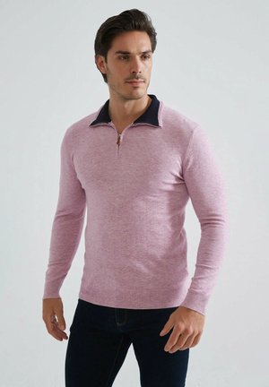 Pull-over à manches longues en rose clair avec un col zippé en marine. Fabriqué en tissu doux avec une texture lisse et des poignets côtelés.